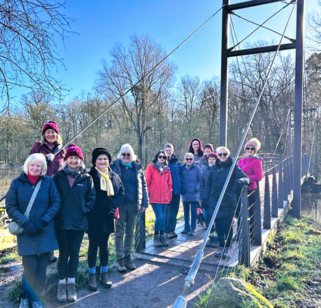 Walkers crossing a bridge in sunshine 