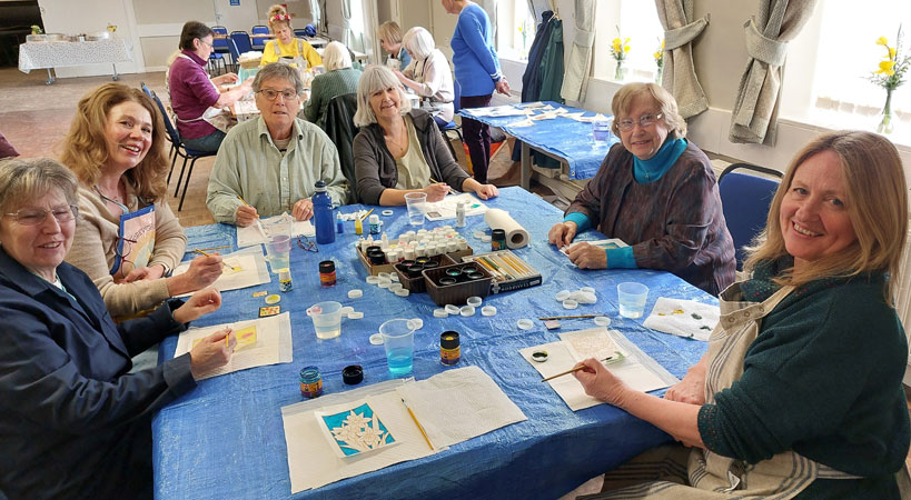 Six ladies look to the camera as they paint silk cards