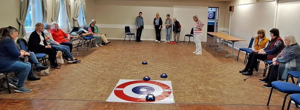 A group of ladies try curling in the village hall