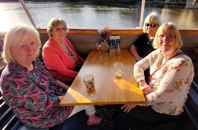 Four ladies sit around a table on a boat