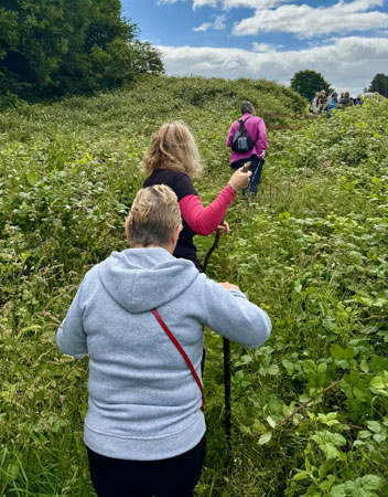Ladies walk along an overgrown footpath