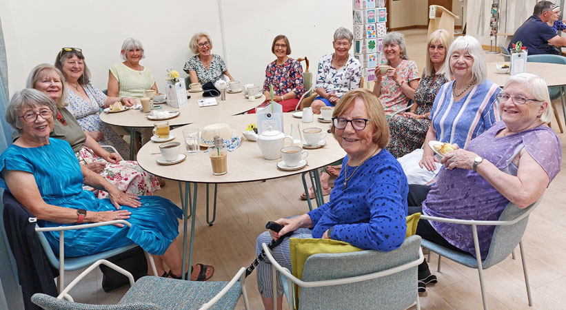 A group of ladies sit around tables drinking coffee