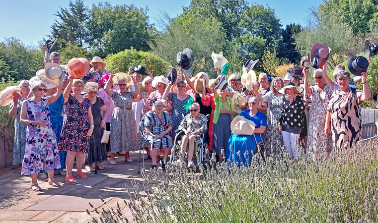 A large group of ladies wave their best hats
