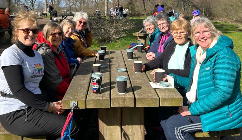 Eight ladies sit outside around a picnic bench