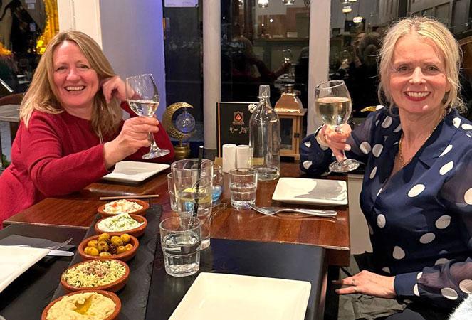 Two ladies raise their glasses in a restaurant