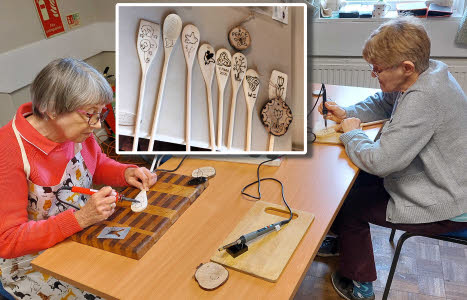 A montage with the main picture showing to ladies working on their pyrography and an inset showing several finished spoons